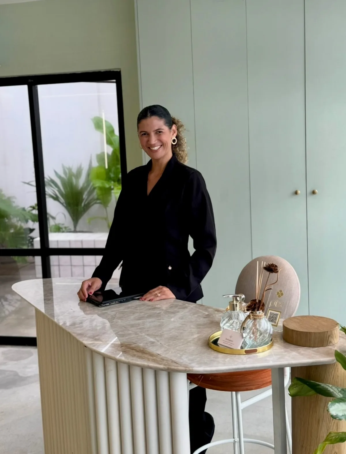 Recepção do Beleziara: balcão canelado em mármore, plantas e luz natural