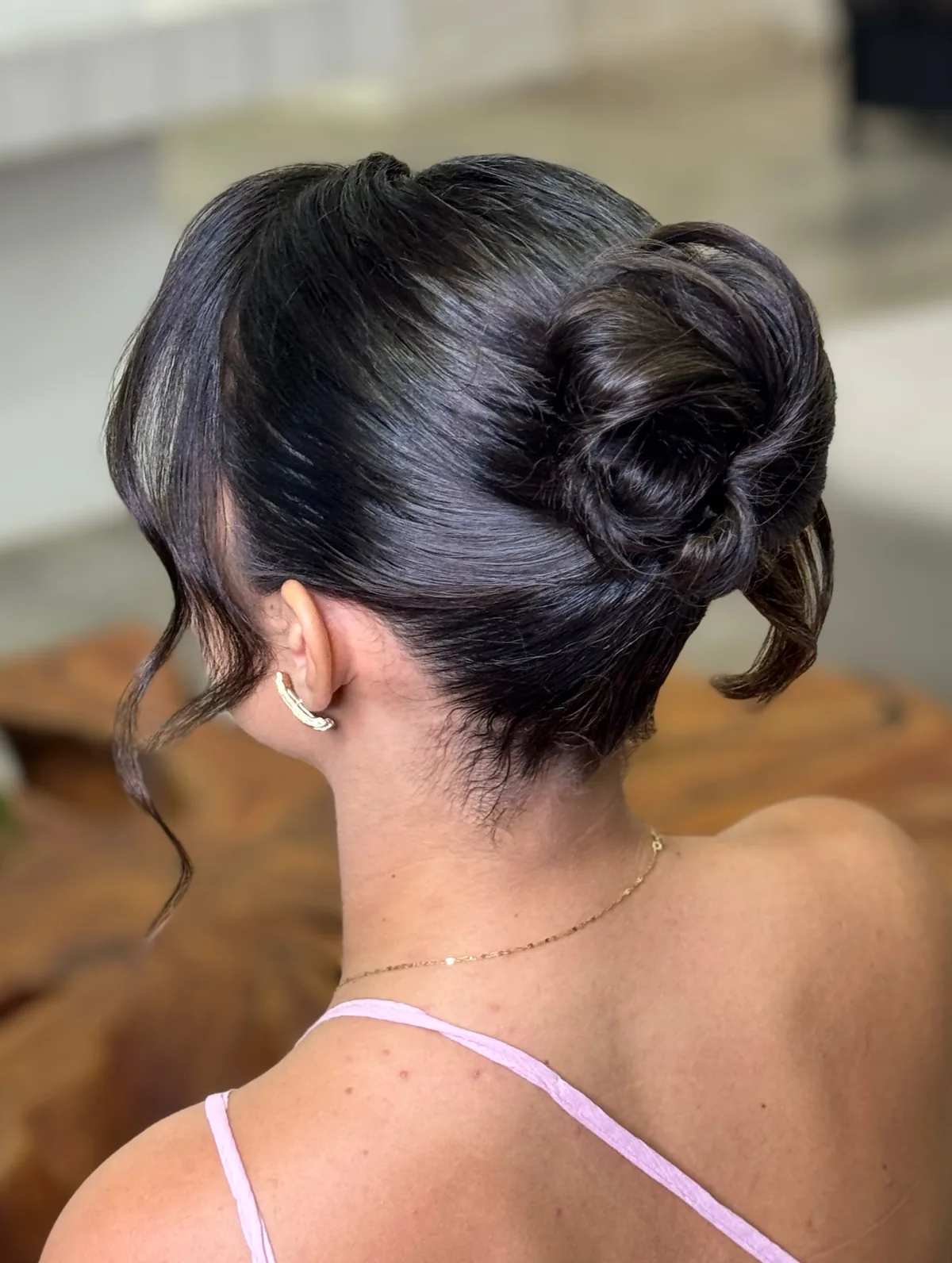 Coque baixo trançado com mechas soltas, visto de costas