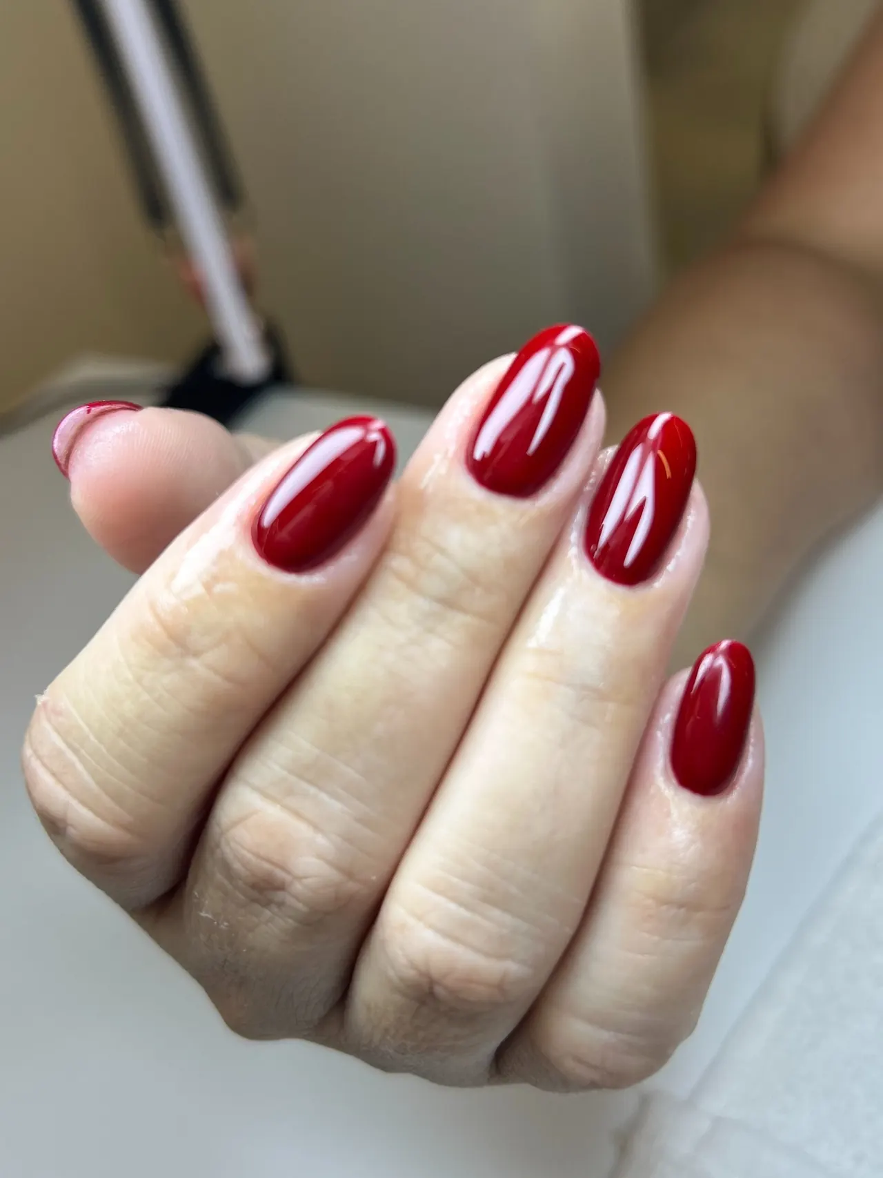 Mão com unhas ovaladas em esmalte vermelho brilhante