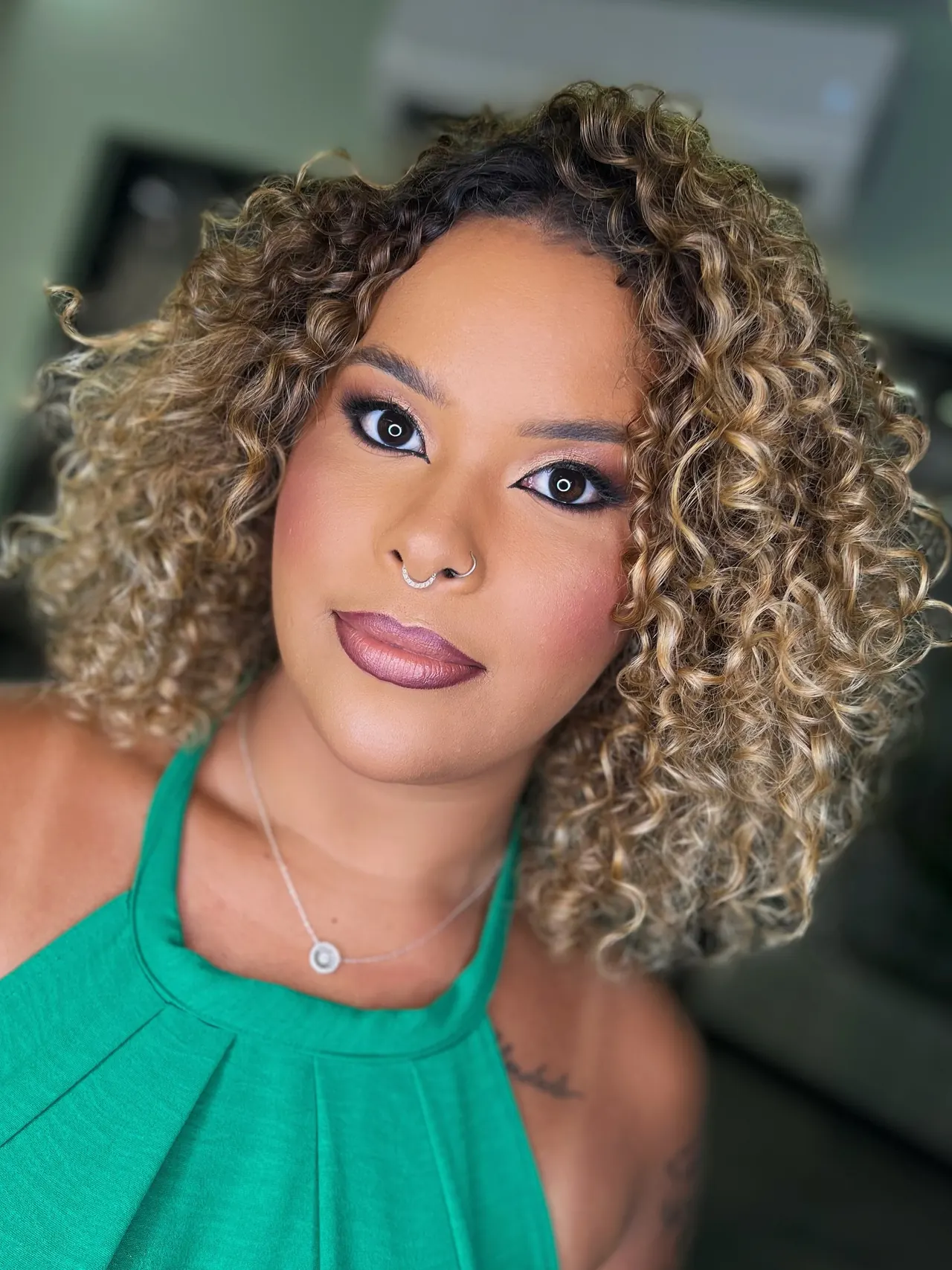 Maquiagem com delineado marcado e batom rosado, em cabelo cacheado com mechas claras